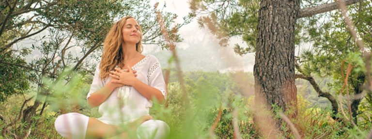 Woman Meditating With Hands On Chest in Forest